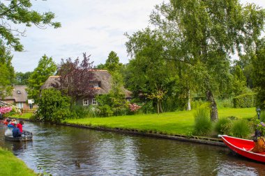 GIETHOORN, NETHERLANDS - 1 Ağustos 2017: Giethoorn 'daki bir kanalda tekne gezisinde bilinmeyen ziyaretçiler. Güzel evler ve bahçıvanlık şehri 