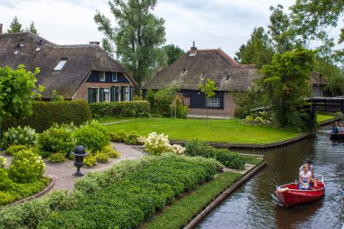 GIETHOORN, NETHERLANDS - 1 Ağustos 2017: Giethoorn 'daki bir kanalda tekne gezisinde bilinmeyen ziyaretçiler. Güzel evler ve bahçıvanlık şehri 