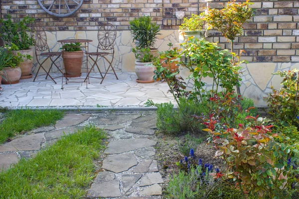 Akdeniz tarzında bahçede güzel bir yer. Izgaralı tuğla duvar ve çiçekli tencereler.