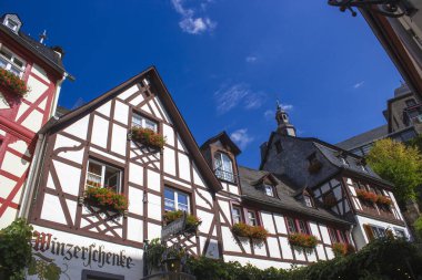 BEILSTEIN, GERMANY - SEPTEMBER 03 2022: Moselle nehri kıyısındaki tarihi köy eski ahşap evleri ve tepelerin tepesinde Metternich kalesinin kalıntıları var.