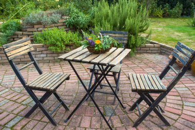 Bahçedeki sarmal bitki ve sandalyeli masa.