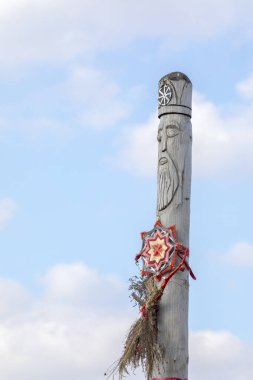Gökyüzüne karşı Slav tanrısının antik ahşap putu. Alnına kazınmış Slav güneş sembolü (Kolovrat).