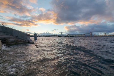 Şiddetli rüzgarlar nedeniyle Neva Nehri 'nde su seviyesi yükseltildi. Vasilievsky Adası 'nın oku ve arka planda Rastral Sütunlar. Gün batımında güzel bulutlar. Saint-Petersburg, Rusya.