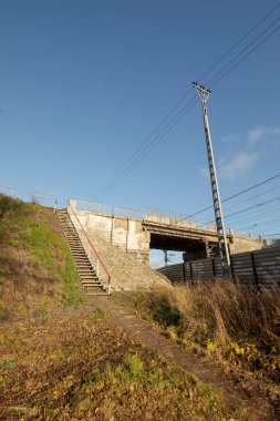 Köprüye giden yaya merdivenleri demiryolu üzerinde. Sonbaharda sarı çimenler.