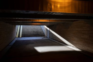 Eski yeraltı yaya tüneli, şehir caddesini geçiyor. Loş tünel bir lambayla kötü aydınlatılmış..