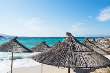 Arnavutluk 'un Maldivler kentindeki zümrüt İyon Denizi' nin zümrüt zeminine karşı palmiye şemsiyeleri