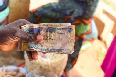 Nakit, para ya da Nijerya para birimi, arka planda yenilebilir gıdalarla yapılan iş alışverişinde el değiştiriyor.
