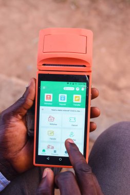 African hands using a point of sales terminal known as POS for business purposes with a finger on the screen on the financial based digital device