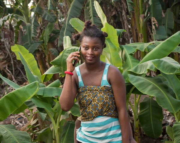 Прекрасна Африканська Мати Немовлям Спині Розумним Телефоном Руці Стоячи Банановій — стокове фото