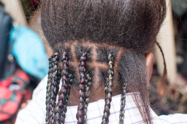  Женская рука парикмахера плетет косички на голове молодой девушки, делая креативную органическую прическу с расчёской