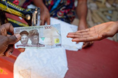 Afrikalı eller para, para ya da Nijerya para değişimi Naira olarak bilinen bir terzi dükkanında iş amaçlı ve arka planda dikiş makinesi ile