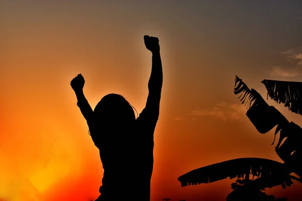 Silhouette of a lady jumping at sunset