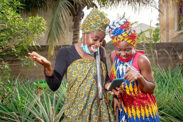 Два Прекрасні Африканські Фермерки Масками Носа Радістю Дивляться Смартфон Шлангами — стокове фото