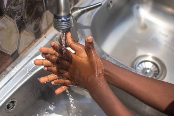 Student or pupil practicing hygienic hands washing with soap under rushing tap water, to enhances healthy lifestyle, prevent germs and bacteria and reduce chances of contacting covid 19