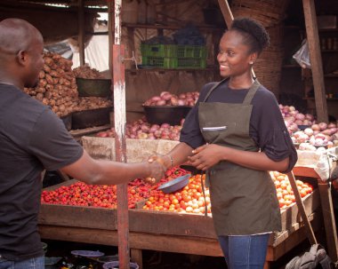 A beautiful and happy African Nigerian female trader, seller, business woman or shop owner preparing to sell goods to her customers in a market