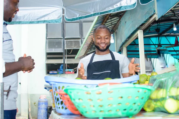 A male African grocery and fruit seller tying his apron in preparation to start selling business for the day