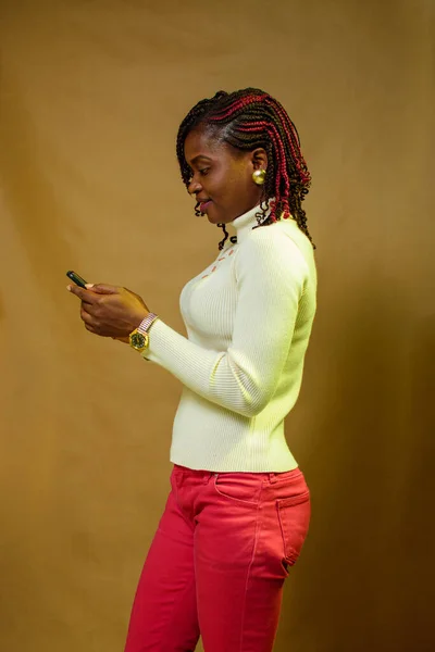 An African lady or woman looking into the smart phone she is holding in her hands