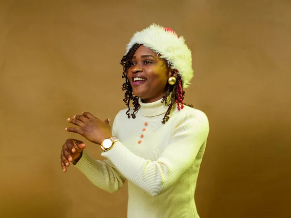 An African lady or woman happily dancing with a Christmas cap on her head