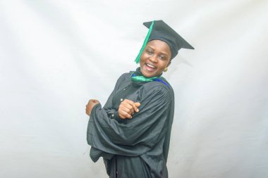 Stock photo of an African female graduand or graduating students moving her body joyfully in her black graduation outfit