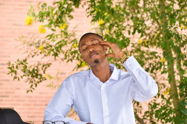 A light skinned african guy wearing white shirt sits with a book in front of him during leisure time