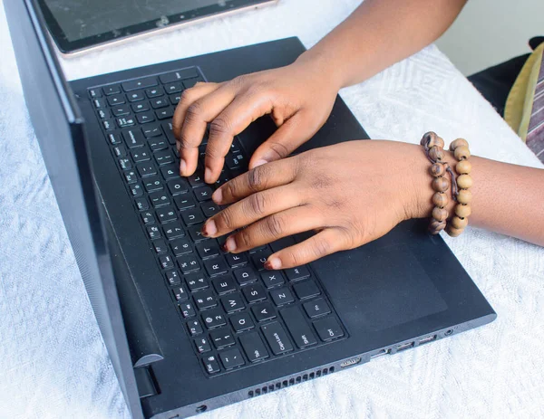 Female African hands with beads using laptop or computer by typing on the keyboard