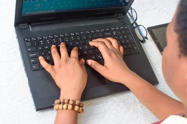 Female African hands with beads using laptop or computer by typing on the keyboard