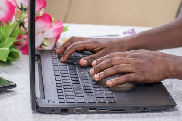 African hands typing or working on a black laptop\'s keyboard