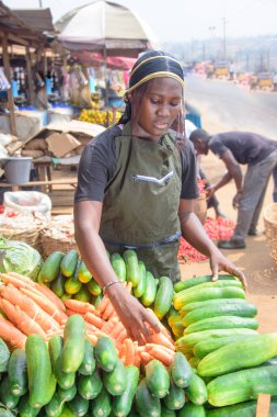 stock photo of female African grocery seller or business woman with apron, standing at her stall in a market, ready to sell to customers