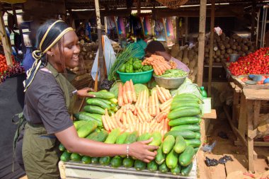 stock photo of female African grocery seller or business woman with apron, standing at her stall in a market, ready to sell to customers