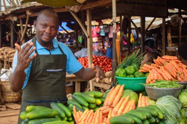 stock photo of male African grocery seller or business man with apron, standing at his stall in a market, ready to sell to customers