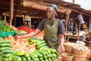 stock photo of female African grocery seller or business woman with apron, standing at her stall in a market, ready to sell to customers