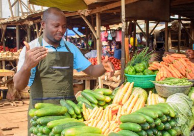 stock photo of male African grocery seller or business man with apron, standing at his stall in a market, ready to sell to customers