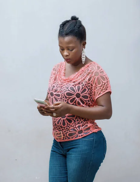 A beautiful happy married African lady, woman or mother from nigeria, using and chatting with a smart phone while standing up