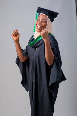 African Nigerian Muslim lady, student or graduand in hijab and graduation gown celebrates her success in education a