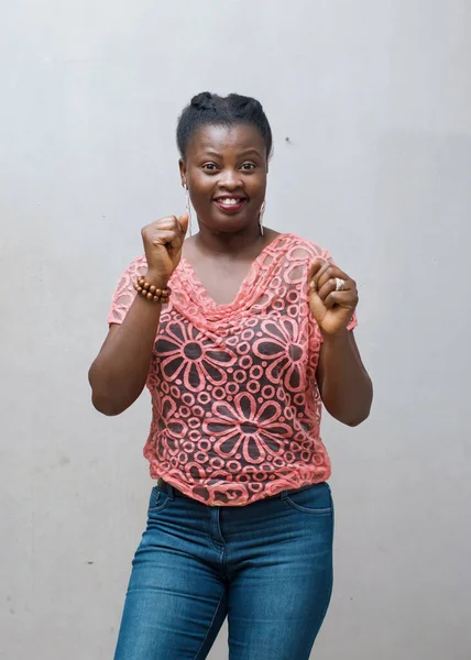 A beautiful happy married African lady, woman or mother from nigeria, dancing in jubilation with her fists up in the air