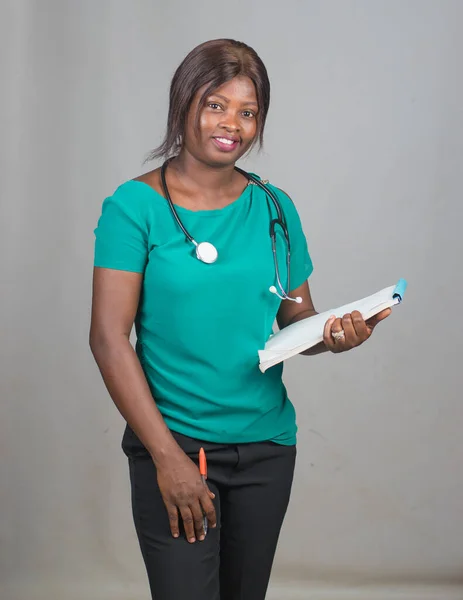 A lady or female medical practitioner from Nigeria with note pad and stethoscope around her neck representing medical practitioners like doctors, nurses, surgeon, physician,dentist among others