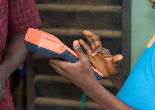 Hands of two african individuals doing business transaction with point of sales terminal know as POS machine in Nigeria
