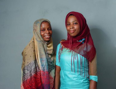 Two happy African Nigerian female muslim sisters or friends with Hijab scarves, prepared to engage the process of prayer or ablution which is more noticeable during ramadan and when going to mosque