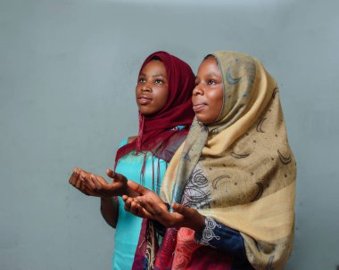 Two African Nigerian female muslim sisters or friends with Hijab scarves, engaging the process of prayer or ablution which is more noticeable during ramadan and when going to mosque
