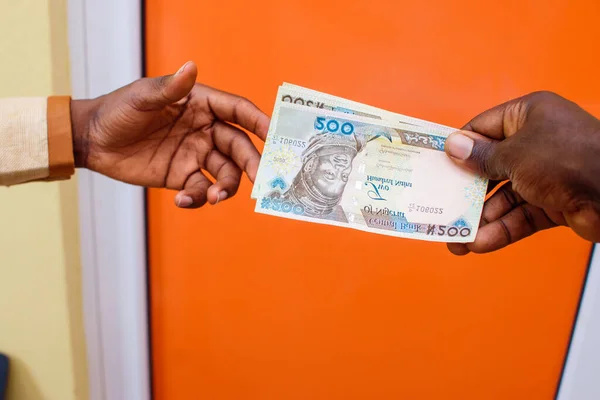 Two african hands receiving or exchanging Nigerian Naira notes, cash or currency