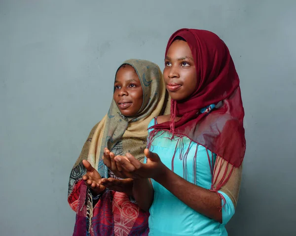 Two African Nigerian female muslim sisters or friends with Hijab scarves, engaging the process of prayer or ablution which is more noticeable during ramadan and when going to mosque