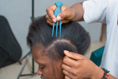 Hands of an hairdresser, stylist or entrepreneur making hair for a female customer in a salon
