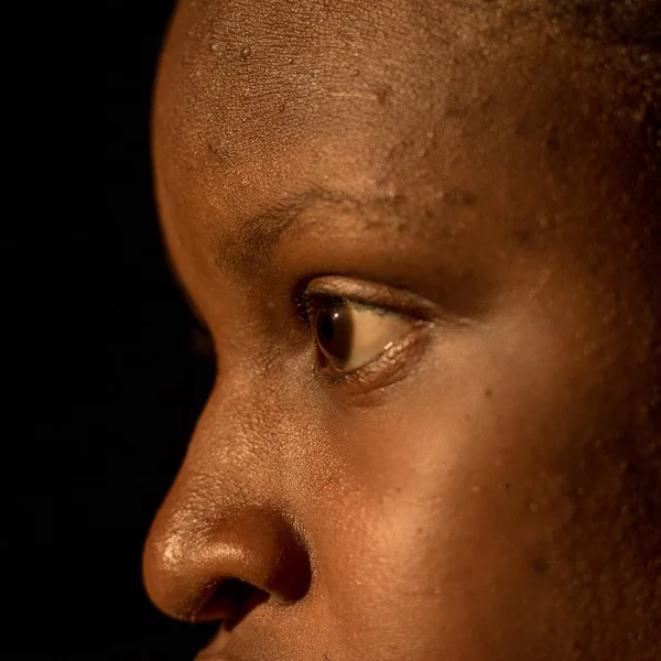 Close up shot of an African female's face, one sided view of a face showing only the eye and nose