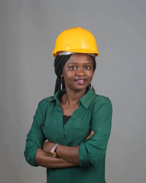 Portrait of a happy African lady or woman from Nigeria with yellow safety helmet representing industrial professionals like construction specialist, builders, architect and engineer