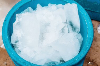 Donmuş buz bloğu açık mavi bir soğutucuda daha küçük bir kısma bölündü