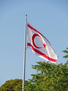 Kuzey Kıbrıs Türk Cumhuriyeti bayrağı adanın kuzey kıyısında gün batımında dalgalanıyor