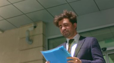 Başarılı bir iş adamının portresi şık bir takım elbise giyiyor. Elinde ofis binalarının yanında dokümanlar var..