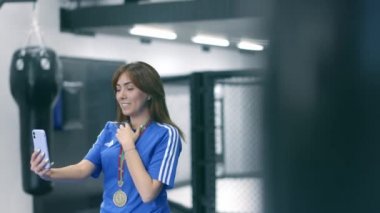 Boksör kız telefonda madalyasını gösteriyor.