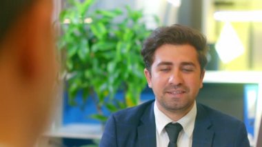 İş adamı bir ofis sandalyesinde oturuyor ve gülümsüyor..