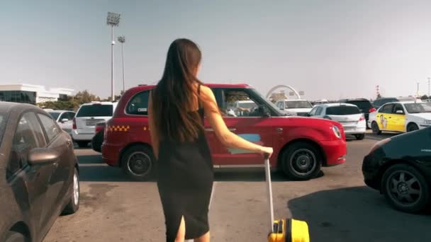 快乐漂亮的女人提着车轮走着走着 走着去出租车 提着手提箱 坐着出租车去现代机场 背景色 — 图库视频影像